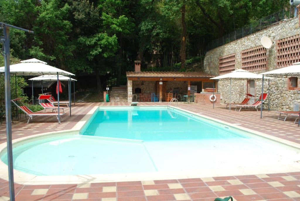 a large blue swimming pool with chairs and umbrellas at Agriturismo San Vettore in Gambassi Terme