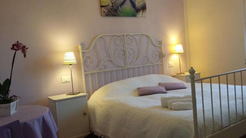 um quarto com uma cama branca e almofadas roxas em B&B Il Paiolo em Desenzano del Garda