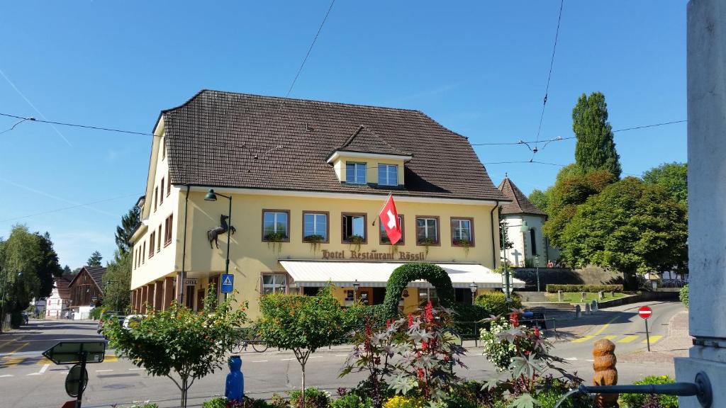 um edifício amarelo com uma bandeira em cima em Hotel Rössli em Basileia