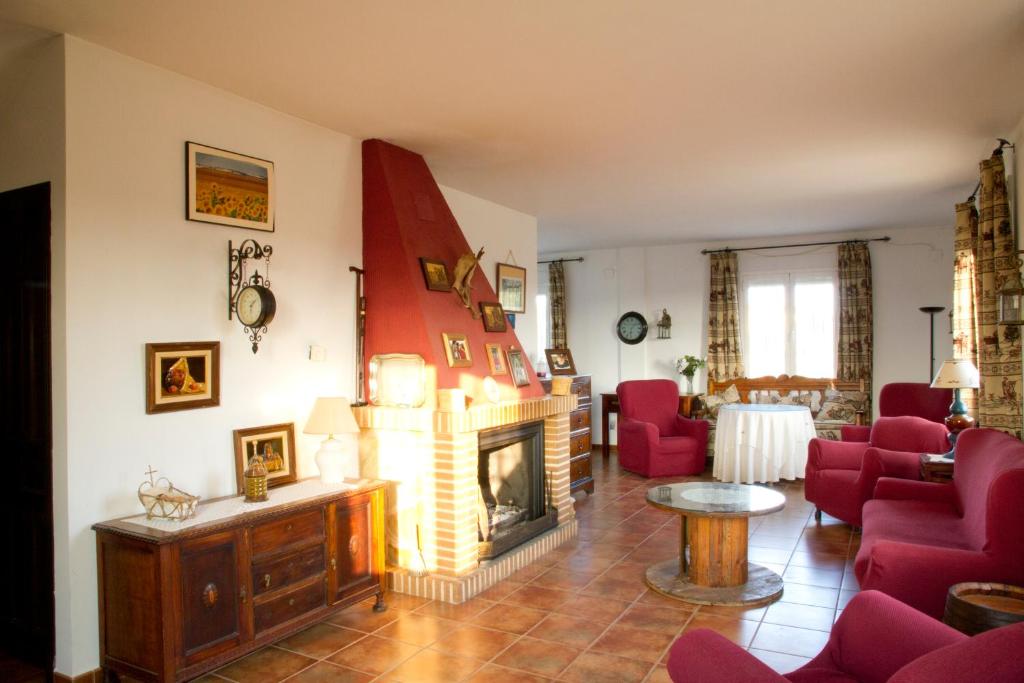a living room with red chairs and a fireplace at Las Candelas in Casas de los Pinos