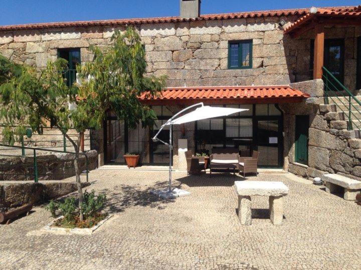 un patio con sombrilla y un banco frente a un edificio en Guesthouse Casa das Abegoarias en Celorico de Basto