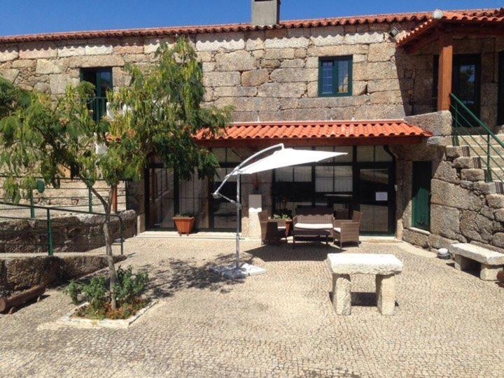 een patio met een parasol en een bank voor een gebouw bij Guesthouse Casa das Abegoarias in Celorico de Basto