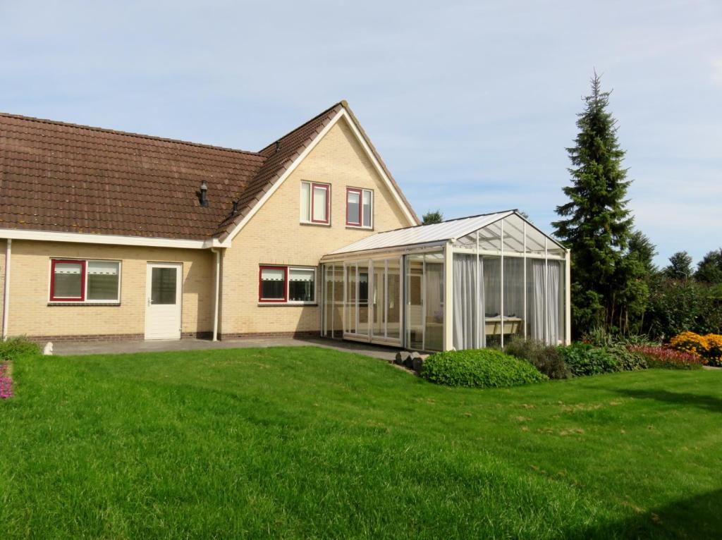 a house with a greenhouse in a yard at Oostvaarders vakantiehuis in Almere