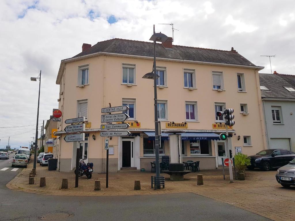 un palo con segnali stradali di fronte a un edificio di Hotel Restaurant l'Avenir a Saint-Pierre-des-Corps