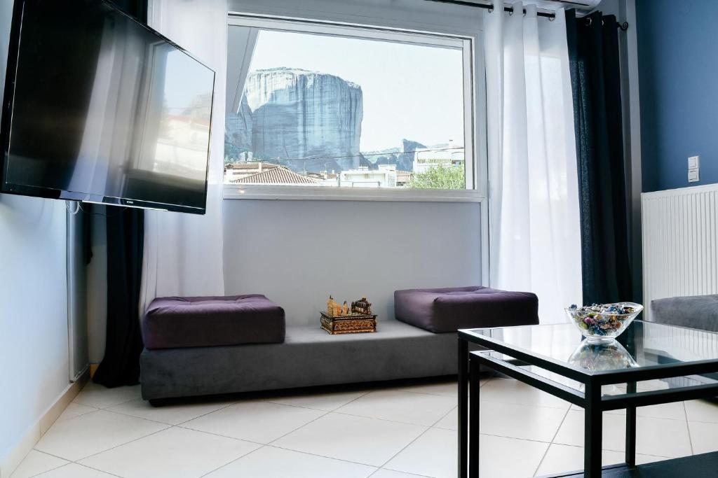 Meteora View Modern Apartments في كالامباكا: غرفة معيشة مع نافذة كبيرة وطاولة