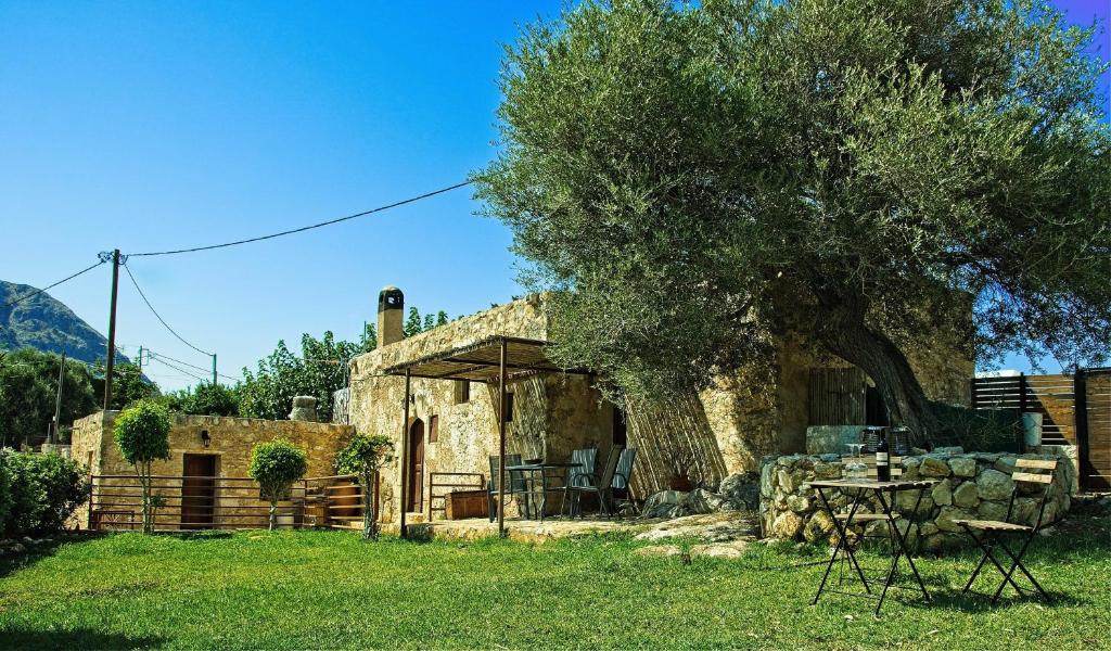 een stenen huis met een tafel en een boom bij Elia House in Megála Khoráfia