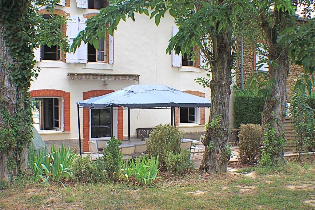 a blue tent in front of a building with trees at Gite La Luciole in Tourtrol
