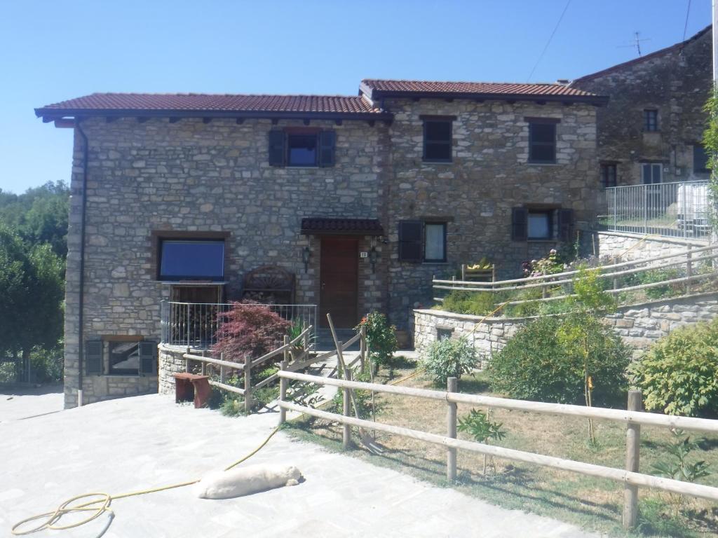 a stone house with a dog laying in front of it at Orto dei Semplici in Farini dʼOlmo