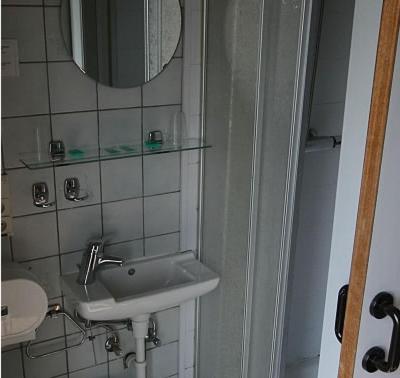 a bathroom with a sink, toilet and mirror at Hotel Anvers in De Panne