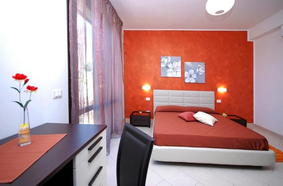 a bedroom with a bed with an orange wall at B&B La Chiocciola in Castelluzzo