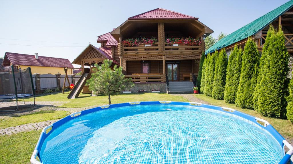 a house with a swimming pool in front of a house at Gostynnyi dim Zatyshok in Dyyda