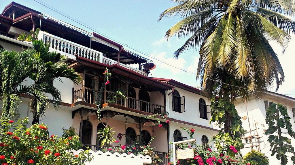 un bâtiment avec un palmier en face dans l'établissement Garden Lodge, à Zanzibar City