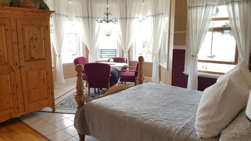a bedroom with a bed and a table and windows at Le Manoir du Vieux Presbytère in Port-Daniel