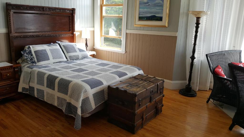 a bedroom with a bed with a blue and white blanket at Le Manoir du Vieux Presbytère in Port-Daniel