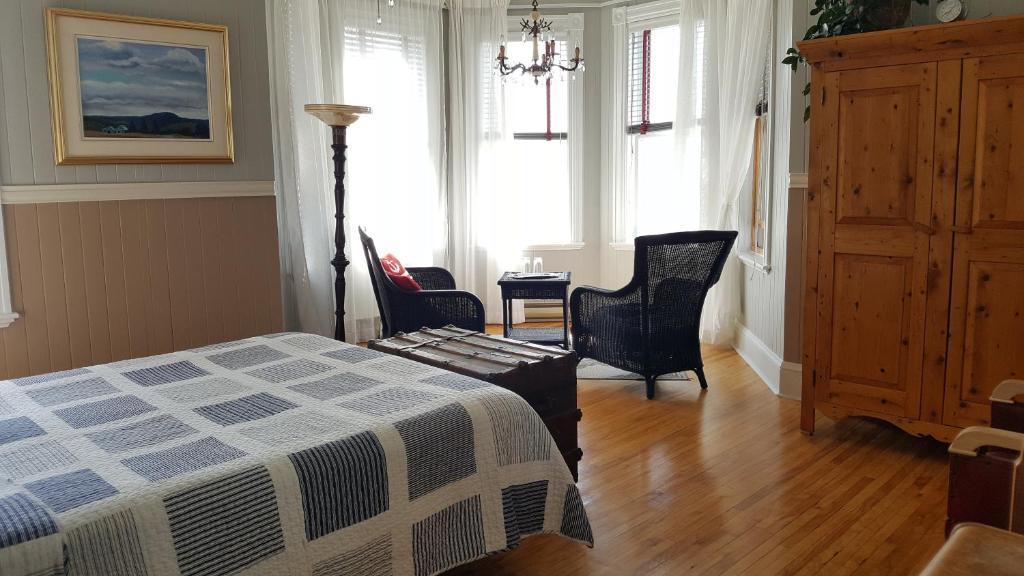 a bedroom with a bed and a table and chairs at Le Manoir du Vieux Presbytère in Port-Daniel
