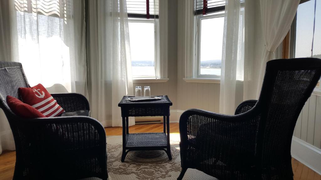 a living room with two chairs and a table and windows at Le Manoir du Vieux Presbytère in Port-Daniel