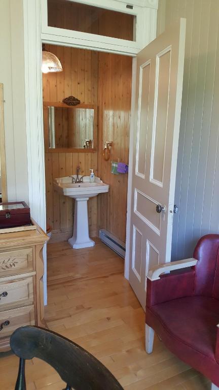 a bathroom with a sink and a red chair at Le Manoir du Vieux Presbytère in Port-Daniel