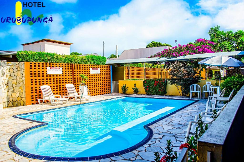 uma piscina com cadeiras e um guarda-sol em Hotel Urubupunga em Ilha Solteira