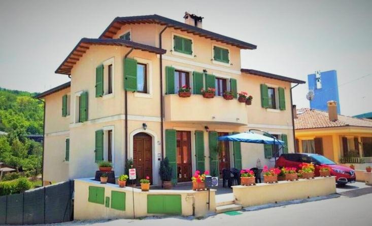a house with green shuttered windows and an umbrella at Miluna B&B in Nocera Umbra