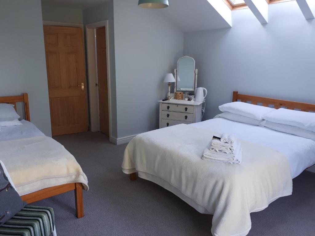 a bedroom with two beds and a chair and a mirror at Field View B&B in Eastrington