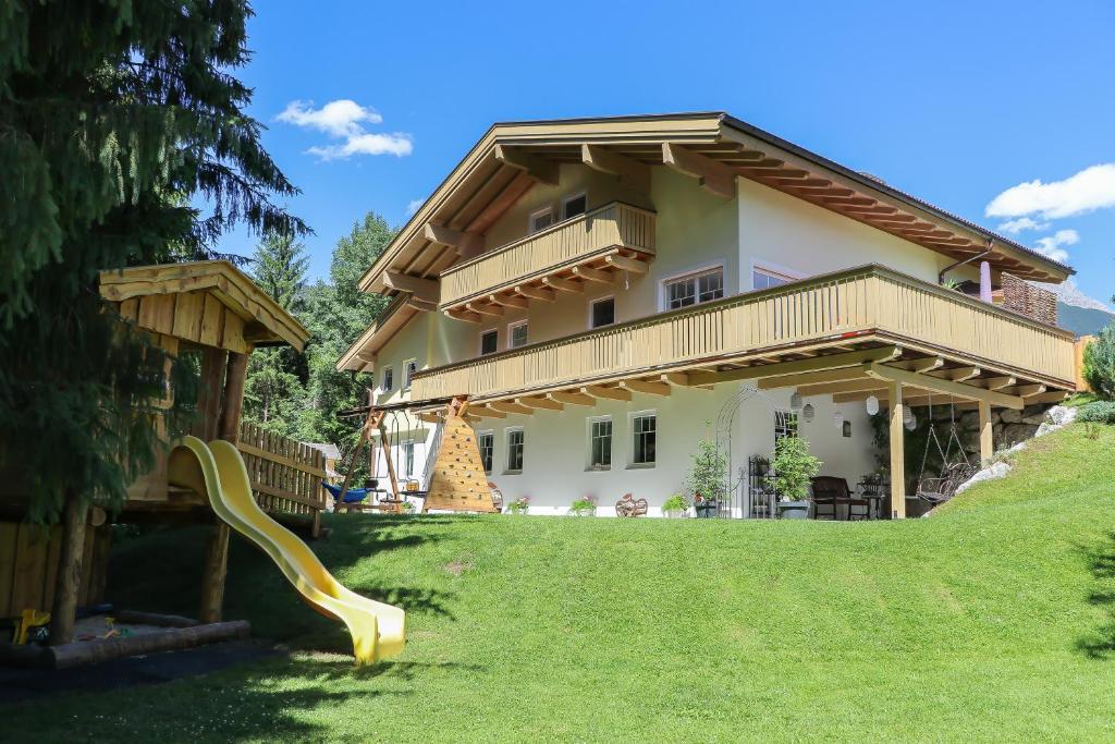 een huis met een groene tuin met een glijbaan bij Appartement Auszeit in Saalfelden am Steinernen Meer