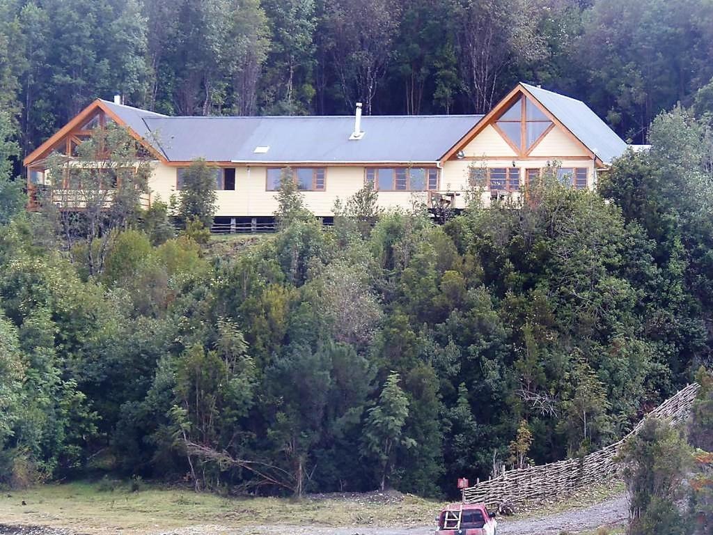 a house on top of a hill with trees at Chile Lodge - Lago Huillinco in Notuél