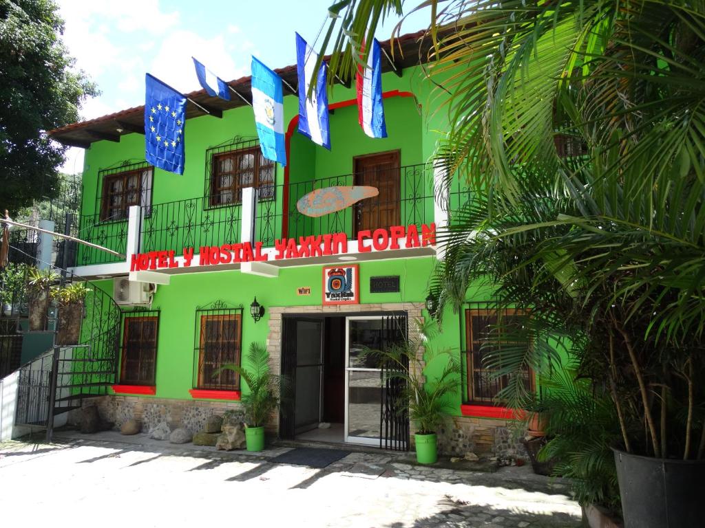 a green building with flags in front of it at Hotel & Hostal Yaxkin Copan in Copán Ruinas