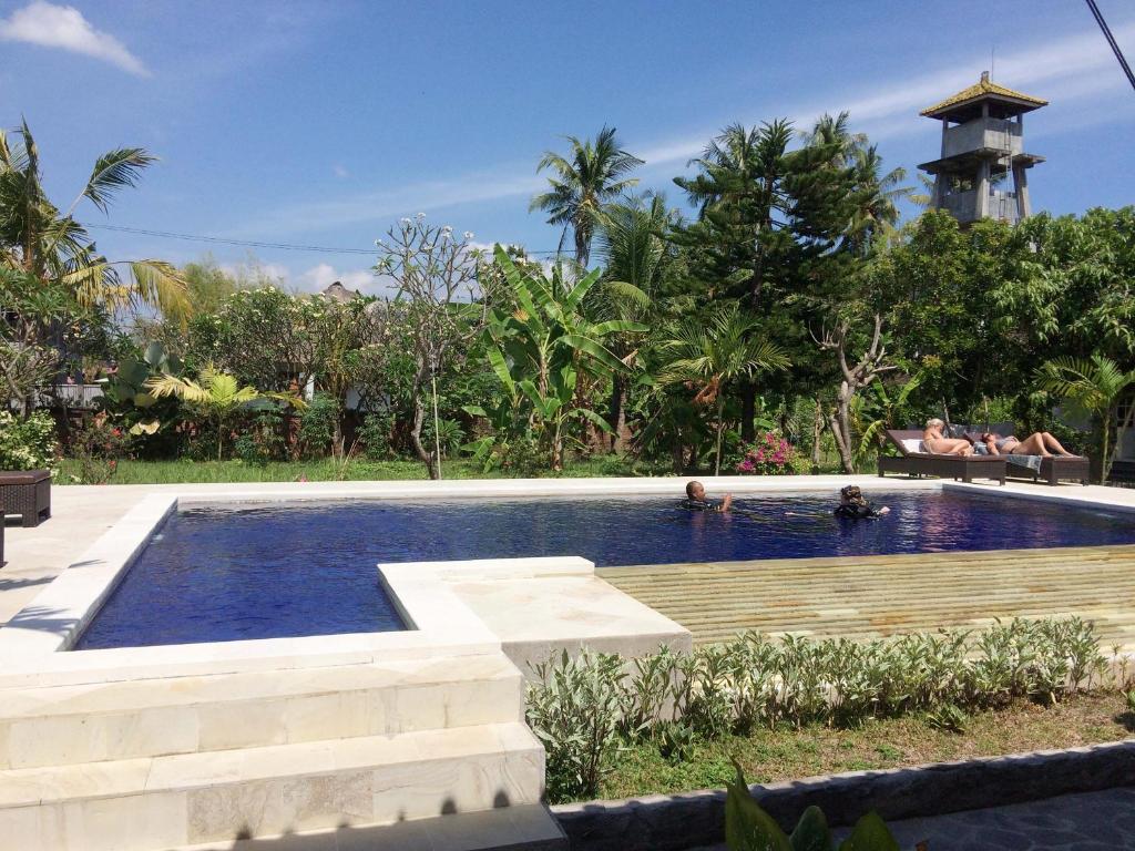 a swimming pool in a resort with people sitting on a bench at Taman Lily's Hotel in Lovina