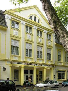 un edificio amarillo con un coche blanco aparcado delante de él en Hotel Haus Union, en Oberhausen