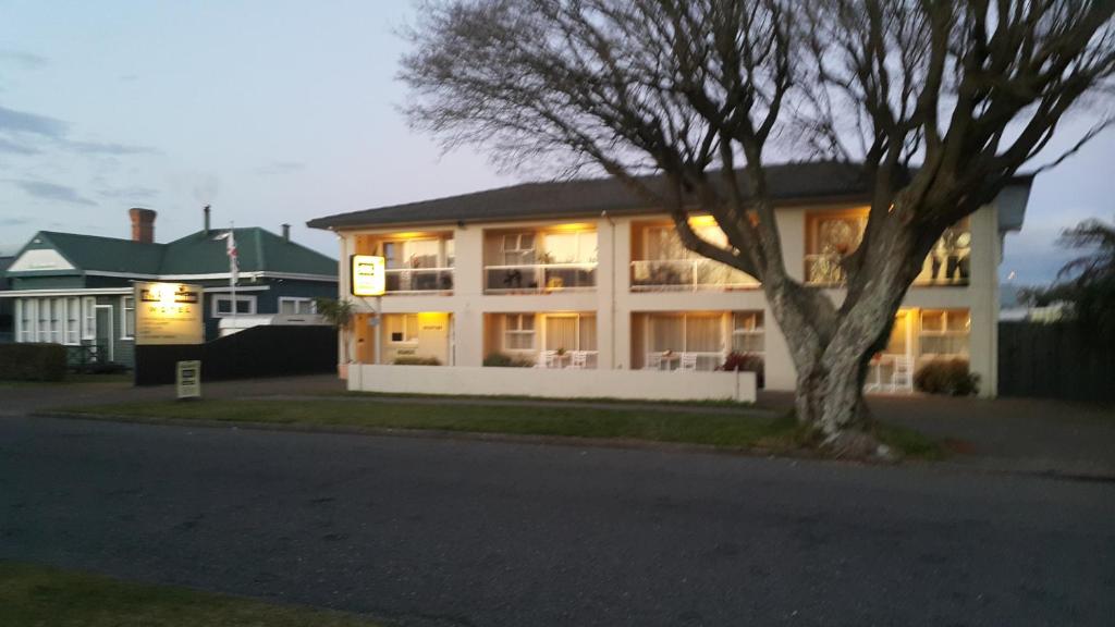 une grande maison blanche avec un arbre en face dans l'établissement Six On Union Motel, à Rotorua