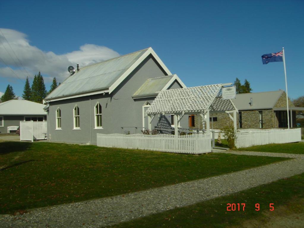 een wit huis met een wit hek ervoor bij St Andrews Church Nave in Ophir