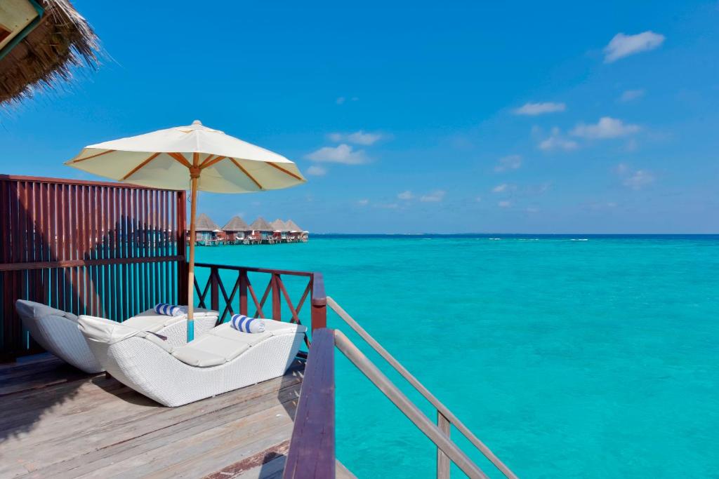 a chair under an umbrella on a deck with the ocean at Thulhagiri Island Resort & Spa in North Male Atoll