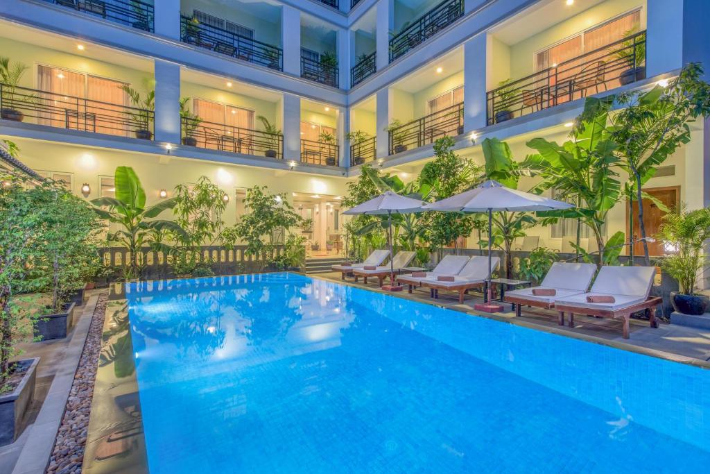 a hotel pool with chairs and umbrellas at Golden Citadel Hotel Siem Reap in Siem Reap