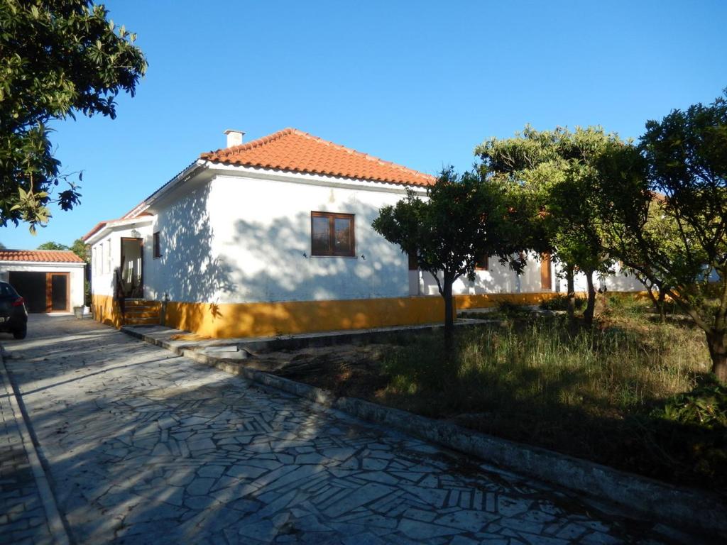 una casa blanca con techo rojo en una calle en Quinta Laranjal da Arrabida, en Palmela