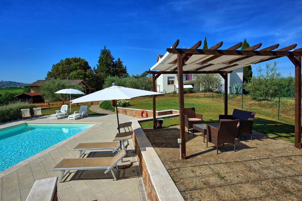 a pool with chairs and umbrellas next to a pool at Country House Tenuta Fornacelle in San Gimignano