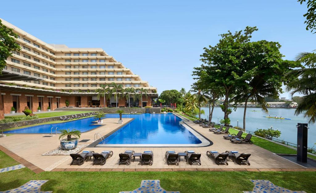 uma piscina com espreguiçadeiras e um grande edifício em Cinnamon Lakeside em Colombo