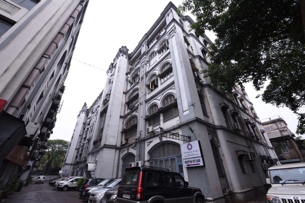 a large white building with cars parked in front of it at Chowdhury's Guest House in Kolkata