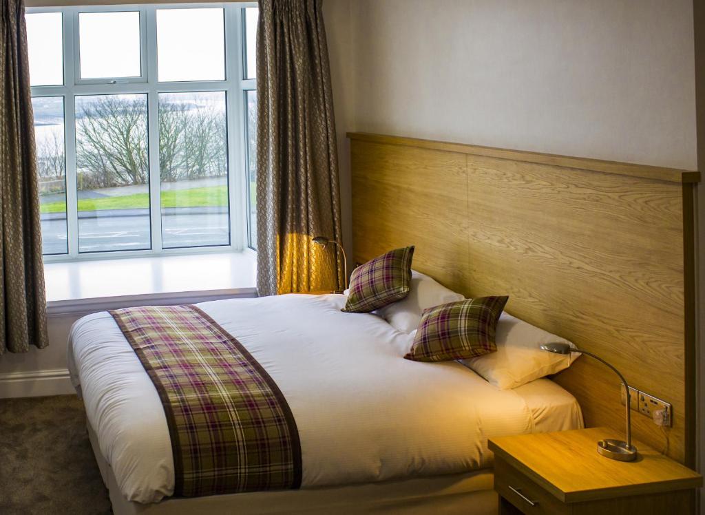 a bedroom with a bed and a large window at King Alfred Hotel in Barrow in Furness