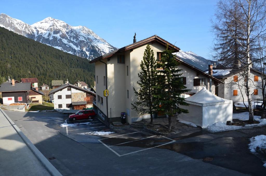 a building with a tree in a parking lot with a mountain at Pensione Cari in Molare