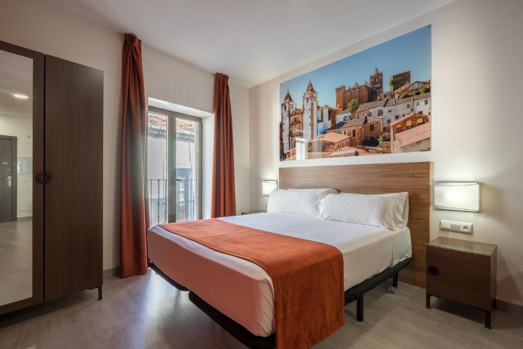 Schlafzimmer mit einem Bett mit Wandgemälde in der Unterkunft Baluart Apartments in Cáceres