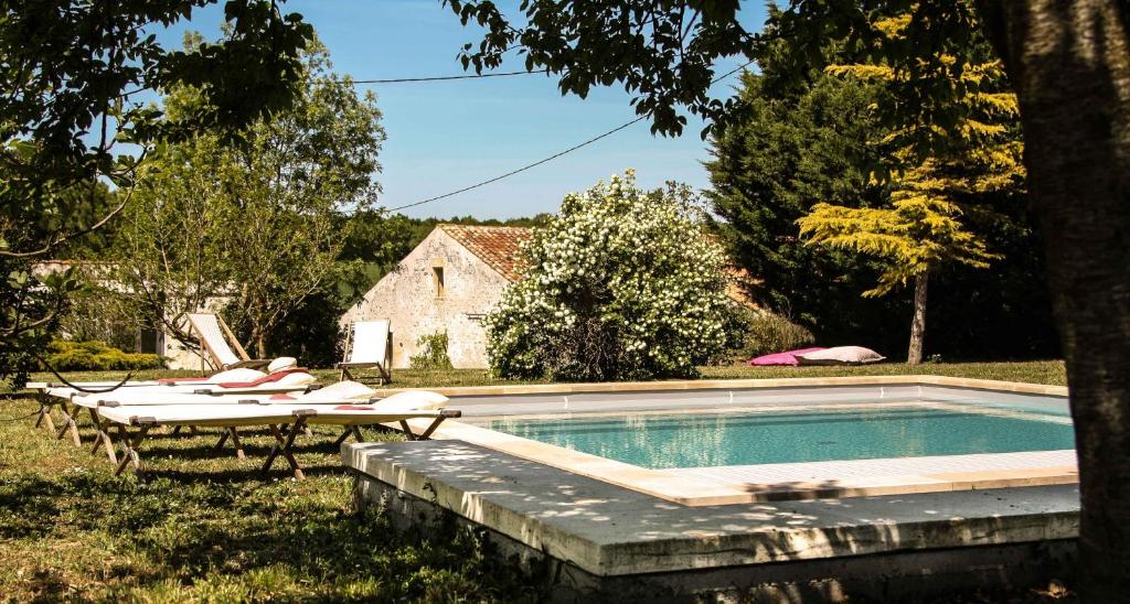 a swimming pool with lounge chairs next to a house at Le Clos du Vallon des Courances in Saint-Coutant-le-Grand