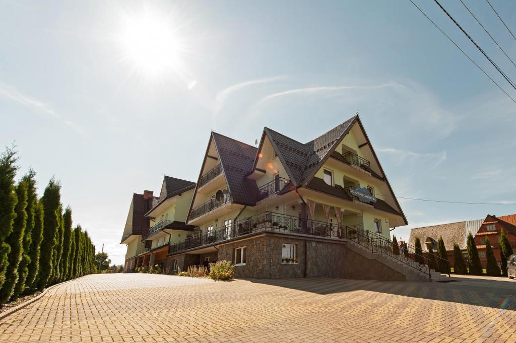 a large house with black roofs on a brick road at Tatrzański Gościniec in Leśnica