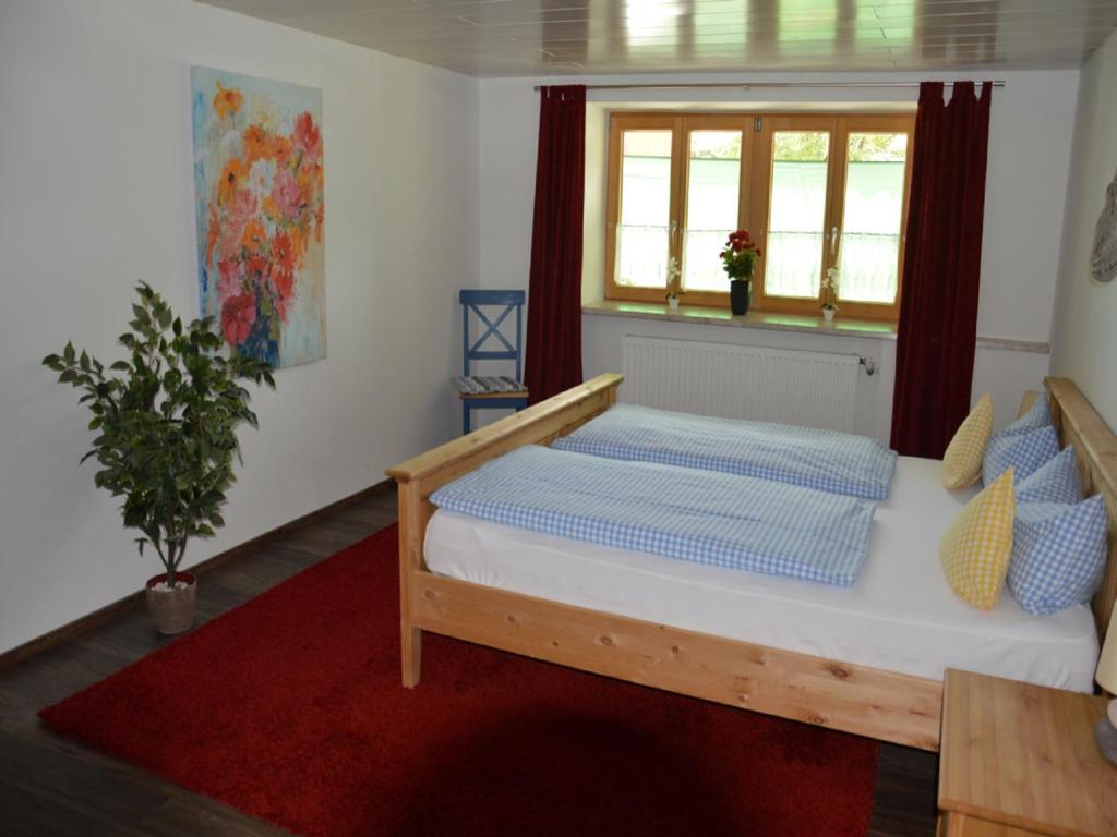 a bedroom with a bed with a red rug and a window at Landgasthaus Mittelallgäu in Betzigau