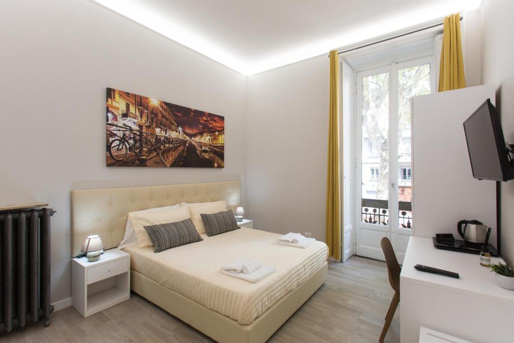 une chambre blanche avec un lit et une télévision dans l'établissement 4Rooms Milano, à Milan