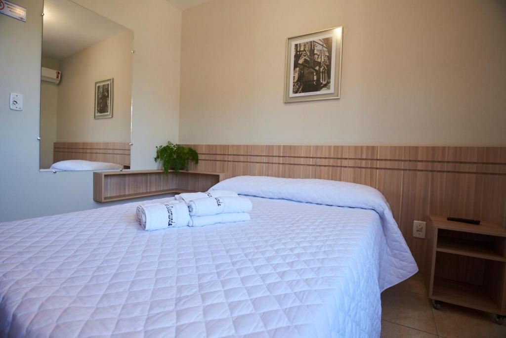 a bedroom with a large white bed with two pillows at Pousada Giramundo in Teixeiras
