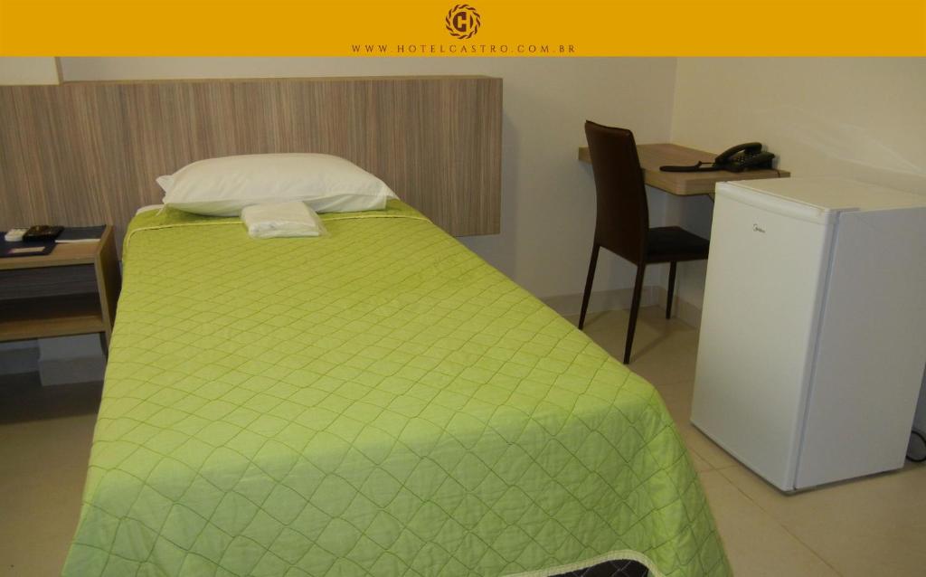 uma cama com um edredão verde num quarto em Hotel Castro em Palmas