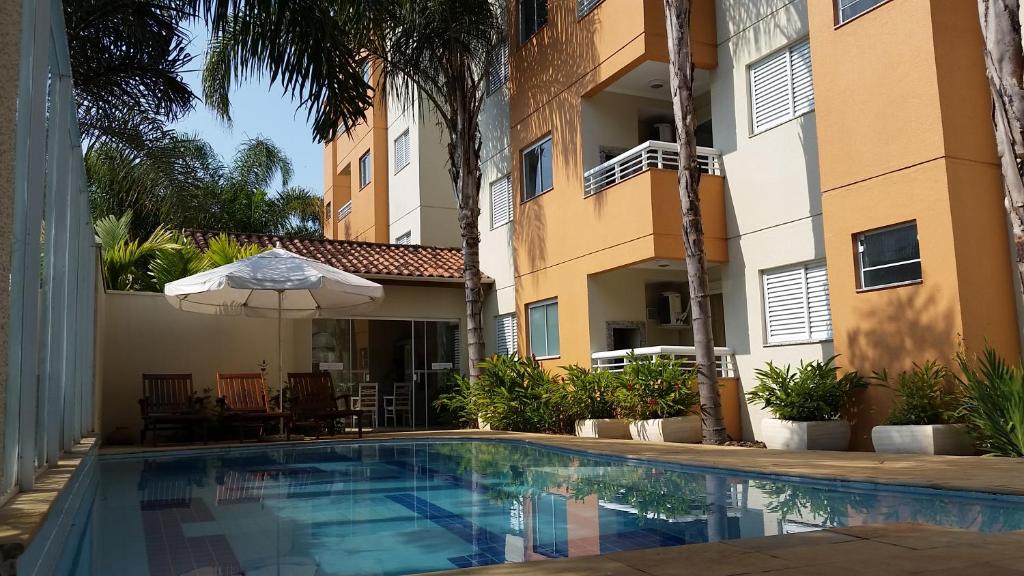 a swimming pool in front of a building with an umbrella at Lorenza by Paramar in Ubatuba