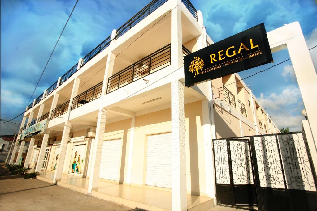 a white building with a sign in front of it at Regal Apartments in Kololi