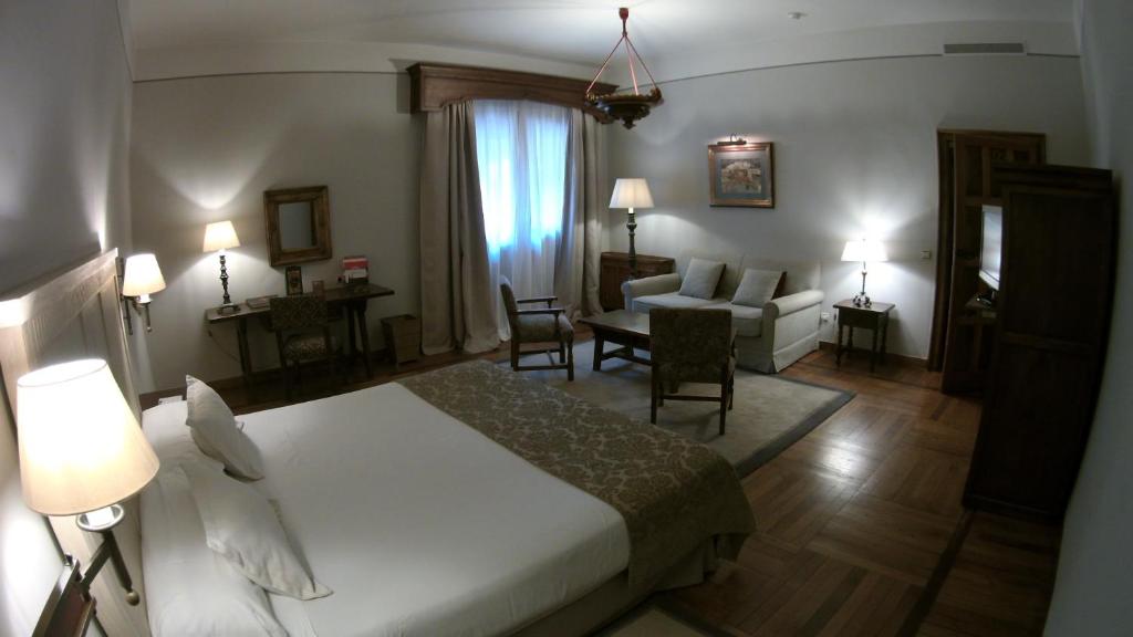 a hotel room with a bed and a living room at Parador de Santiago - Hostal Reis Catolicos in Santiago de Compostela