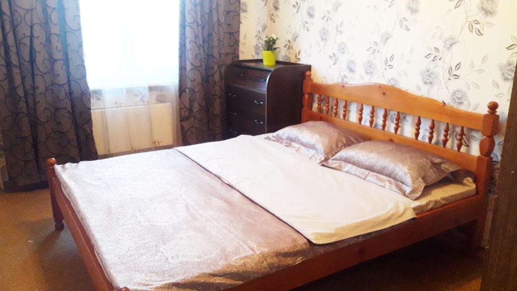 モスクワにあるАпартаменты Генерала Белова 19のベッドルーム1室(木製ベッド1台、枕付)、窓が備わります。